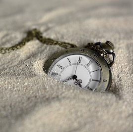 a pocket watch partially submerged in sand