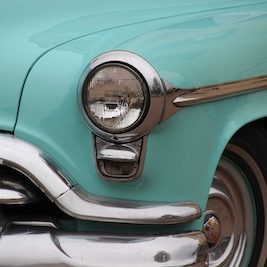 close up of a headlight of a turquoise Oldsmobile