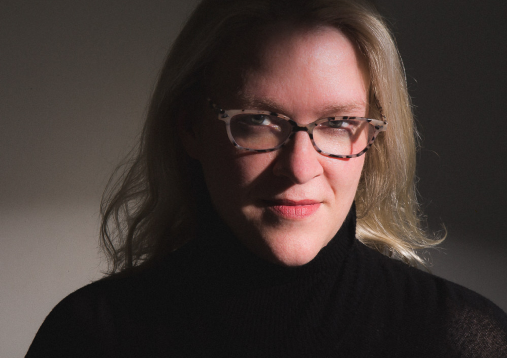 Headshot of Megan Stielstra, a blond woman wearing glasses and a black turtleneck