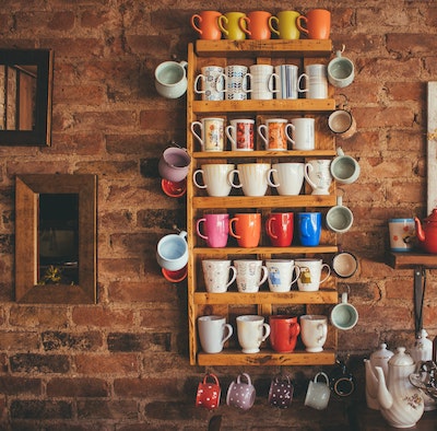 colorful coffee mugs on shelves against a brick wall