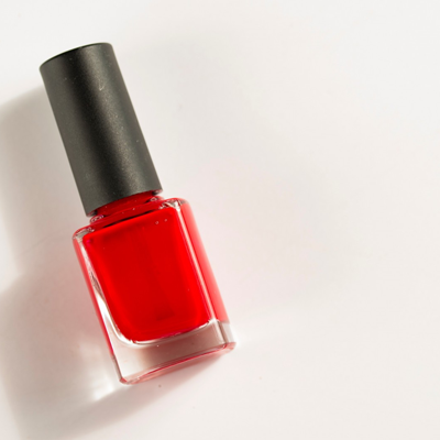 A black-capped bottle of red nail polish on a white background