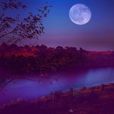 River banked on both sides by hills with the full moon bright in the sky. The sky and water both look purple.