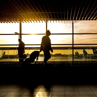 People carrying luggage at airport against sunset