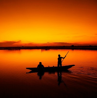 Two people on fishing boat at sunset