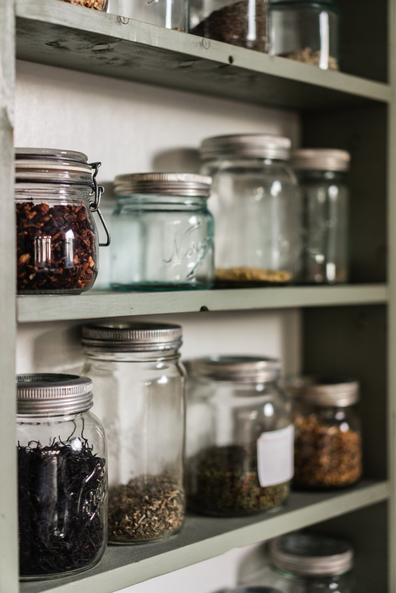 A shelf with mason jars, some filled, some empty