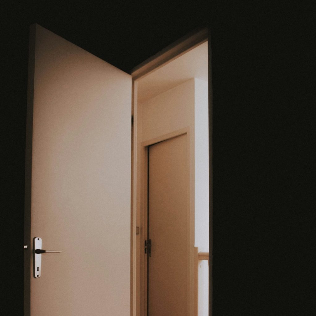 A white door open to a dark hallway