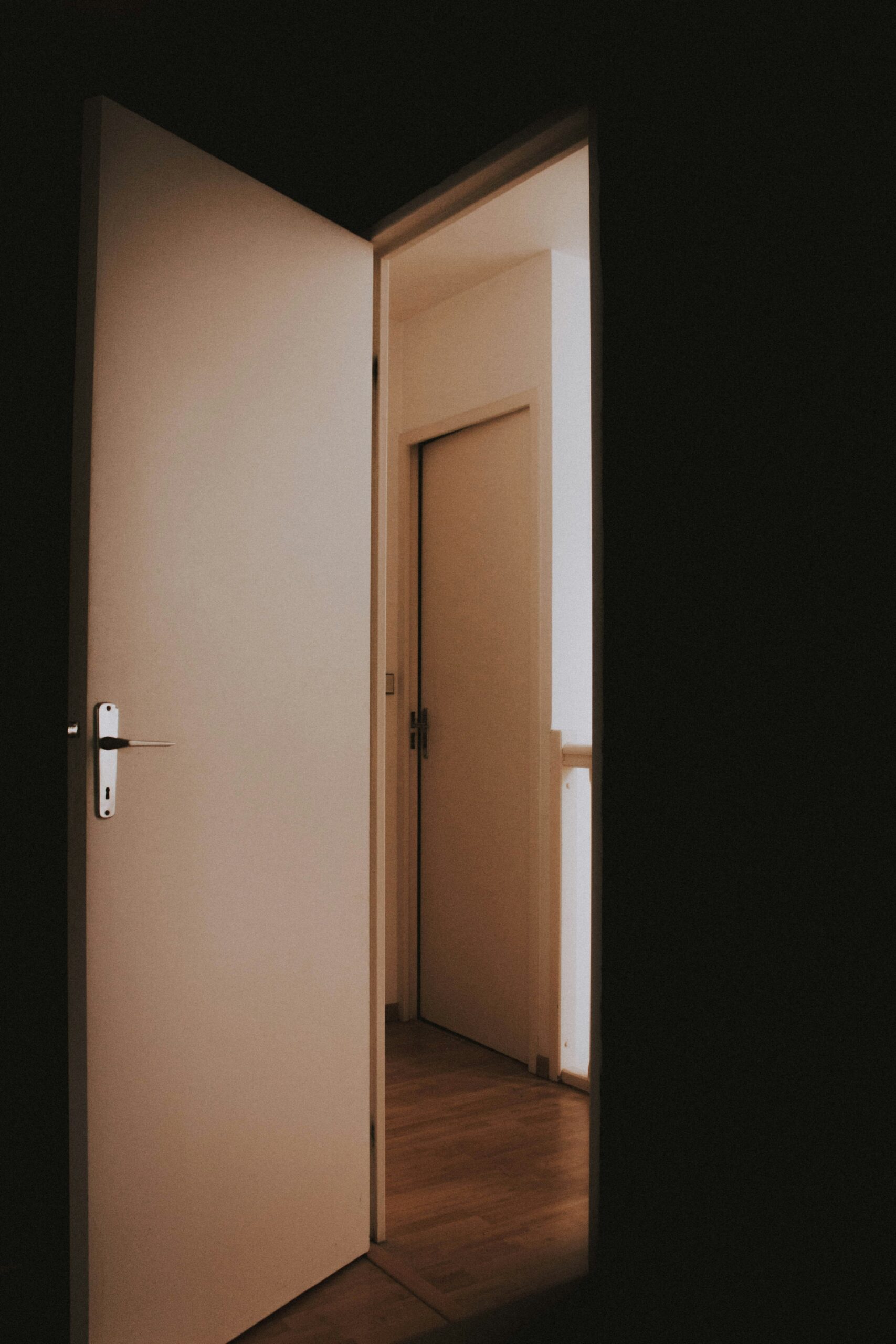 A white door open to a dark hallway
